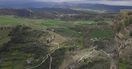 Wall Mural - High angle viewpoint of Ronda countryside with green fields and cloudy landscape pan left