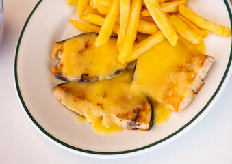 Canvas Print - Roast swordfish slices in hollandaise sauce with French fries dished up in a plate