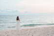 © Jo Panuwat D - Happy traveler woman in white dress enjoy beautiful sea view, young woman standing on sand and looking ocean at tropical beach. Freedom, relaxing, vacation holiday and summer travel concept