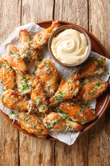Wall Mural - Chicken Parmesan Wings are oven-baked or air-fried and then coated in a buttery garlic parmesan sauce closeup on the plate on the table. Vertical top view from above