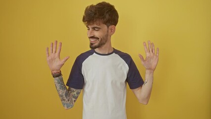 Wall Mural - Cheerful young hispanic man standing tall, confidently showing the number ten with fingers, pointing upwards. joyfully smiling over isolated yellow background.