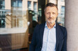 © contrastwerkstatt - Portrait of a confident mature businessman standing against a pillar in an urban setting, conveying professionalism and experience.