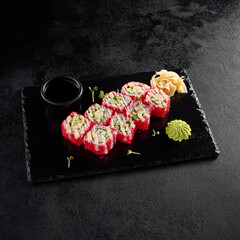 Sticker - California roll with tobiko and crab, served on a black slate with soy sauce and wasabi