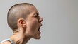 © Panuma - Side profile of a person with a shaved head shouting, expressing strong emotion and intensity against a plain background.