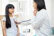 © anon - doctor in a white coat conducting a health check on a girl, father by her side.