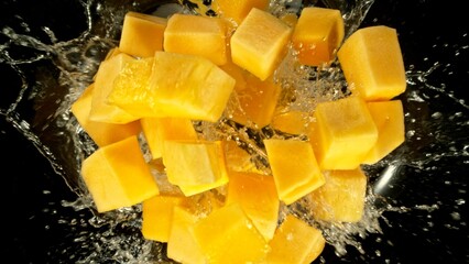 Poster - Freeze Motion of Flying Mango Slices into Water, Black Background.