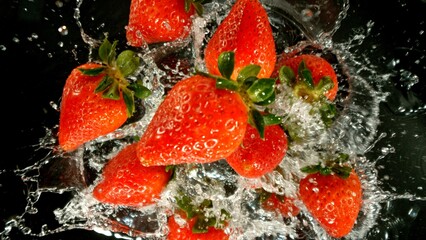 Poster - Freeze Motion of Flying Strawberries into Water, Black Background.