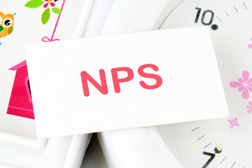 The word Net Promoter Score. NPS text on the business card on the background of the clock