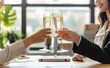 © ant - Close up of two business women clinking champagne glasses in an office