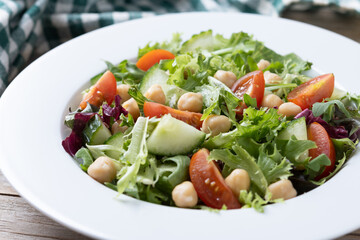 Canvas Print - Healthy chickpea salad with tomato,lettuce and cucumber on wooden table. Close up