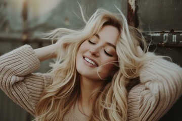 Poster - Happy young woman with blonde, windswept hair enjoys a carefree moment outside