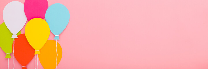 Wall Mural - Colorful balloon shapes from application paper with white strings on light pink table background. Pastel color. Closeup. Wide banner. Empty place for inspirational text, quote or sayings. Top down vie