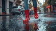 © Nuth - Red rubber boots splashing in a puddle on a rainy day
