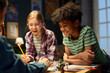 © pressmaster - Cheerful kids standing by table with new board game, looking at dice thrown by one of boys and laughing while enjoying play