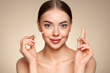 Wall Mural - portrait beautiful young woman with clean fresh skin. model with foundation makeup bottle. cosmetolo