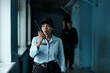 © pressmaster - Young female security guard in uniform and cap speaking on walkie-talkie to her colleague while moving along corridor of building