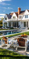 A photo of the front view across an open lawn with two white chairs facing towards it, in the background is a large classic colonial house and pool area.