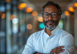 © AmayaGB - Hombre moreno con barba y gafas 40s - 50s, ejecutivo, con los brazos cruzados, en un pasillo en un ambiente tenue empresarial, de frente, a un lado de la imagen, denota confianza, seguridad, ámbito IT