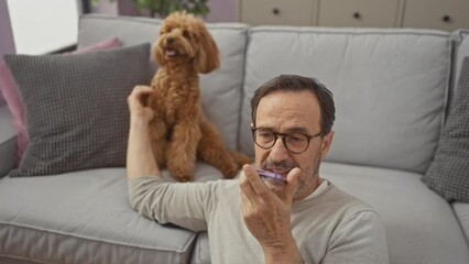 Poster - Middle-aged hispanic man sending a voice message while relaxing with his poodle in a cozy living room.