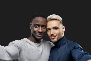 Hugging casual handsome young men taking selfies on a neutral isolated background