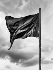 Wall Mural - A black flag is blowing in the wind. The flag is on a pole and the sky is cloudy