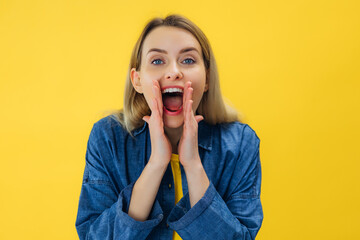 cheerful surprised young woman keep hands near mouth wshispers secret, share gossips isolated over yellow background.