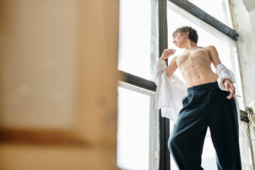 A woman stands confidently in front of a window, showcasing his sophisticated style.