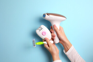 Wall Mural - A modern epilator for removing unwanted body hair at home, wax strips, a mechanical epilator and a razor on a colored background in female hands