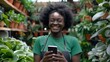© Nataliya - Young african american shopkeeper girl smiling happy using smartphone at florist. Online shopping, flowers delivery