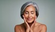 © Marko - gorgeous senior older woman with closed eyes touching her perfect face skin, beautiful portrait mid 50s aged woman, facial antiage lift skin care products, isolated on light grey background