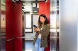 © Alba Vitta/Stocksy - Woman inside elevator using phone