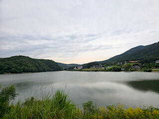 A lake with a cloudy sky in the background. The water is calm and the sky is overcast