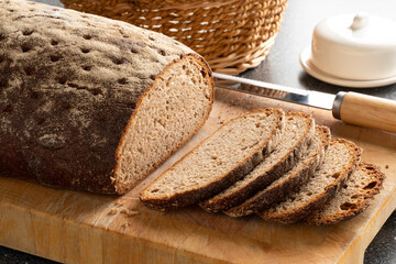 Wall Mural - Sliced classic Sourdough mixed rye loaf of bread close up on a cutting board