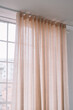 © Adrian Cotiga/Stocksy - Soft, sheer curtains with a glimpse of a window