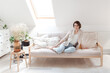 © Lea Csontos/Stocksy - Young woman relaxing on her white sofa in her white room.
