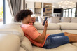 © Wavebreak Media - A biracial young male relaxing at home, holding smartphone