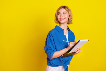 Sticker - Photo of nice young girl write clipboard look empty space wear blue shirt isolated on yellow color background