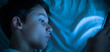 © Pixel_Studio_8 - Child with insomnia lying in bed looking at the cell phone at night.