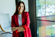 © BGStock72 - Confident young professional in red blazer smiling at modern office environment