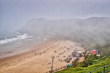 Foggy beach with people relaxing and tents in Tynemouth Beach