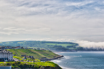 Wall Mural - Scenic coastal view with green hills and small town in Whitby, North Yorkshire