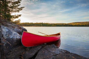 Wall Mural - red wood canoe on rocky island in the boundary waters at sunrise on a bright fall morning