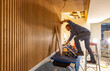 © Raymond Forbes LLC/Stocksy - Blue Collar worker Carpenter building Vertical wood paneling wall