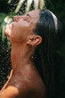 © Atolas/Stocksy - Woman taking a shower outdoors