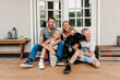 © Melissa Milis Photography/Stocksy - family posing in front of their home with their dog acting funny