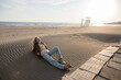 © Evgenij Yulkin/Stocksy - Young woman under the warm spring sun on the beach