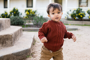 two year old happy toddler boy with dark hair is camera aware and looks at the camera happily