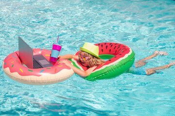 Wall Mural - Laptop in pool. Summer business. Child remote working on laptop in pool. Little business man working online on laptop in summer swimming pool water.