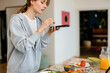 © DZ FILM/Stocksy - A woman takes pictures of cooked food