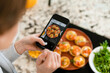 © DZ FILM/Stocksy - A woman takes pictures of cooked food